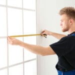 Service man measuring window for installation indoors